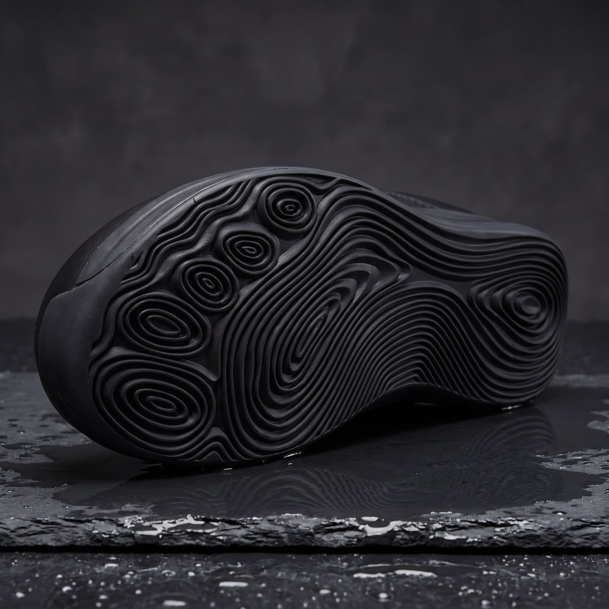 Ledger's rippled black outsole on wet slate